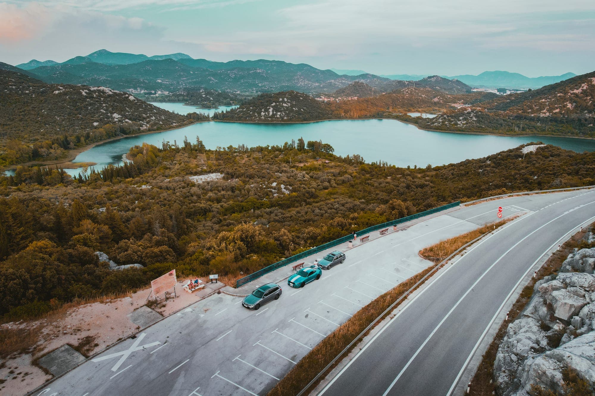 Kolóna áut na pobrežnej ceste nad zálivom, záber z dronu