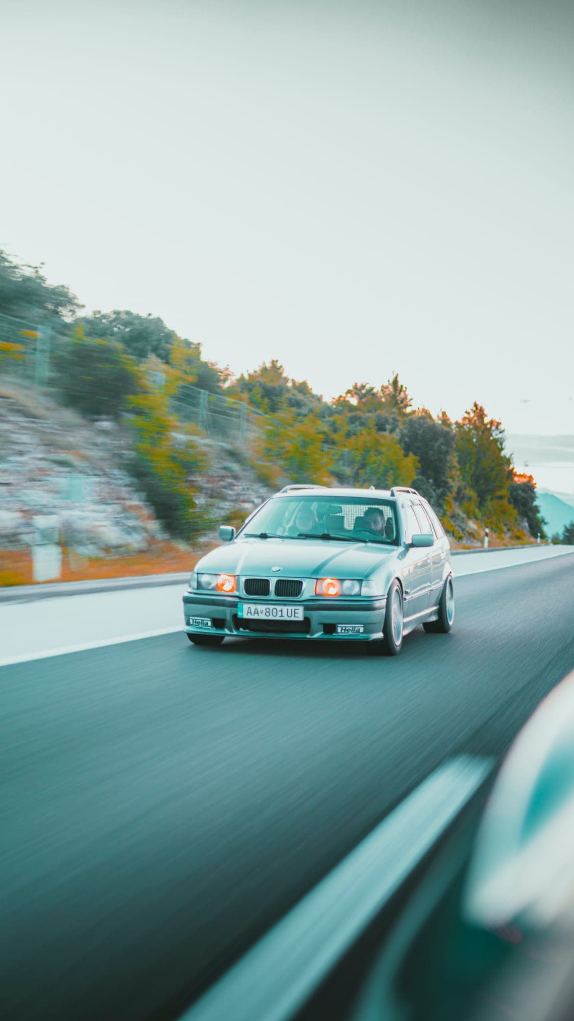 Strieborné BMW na ceste pomedzi skaly, záber z idúceho auta