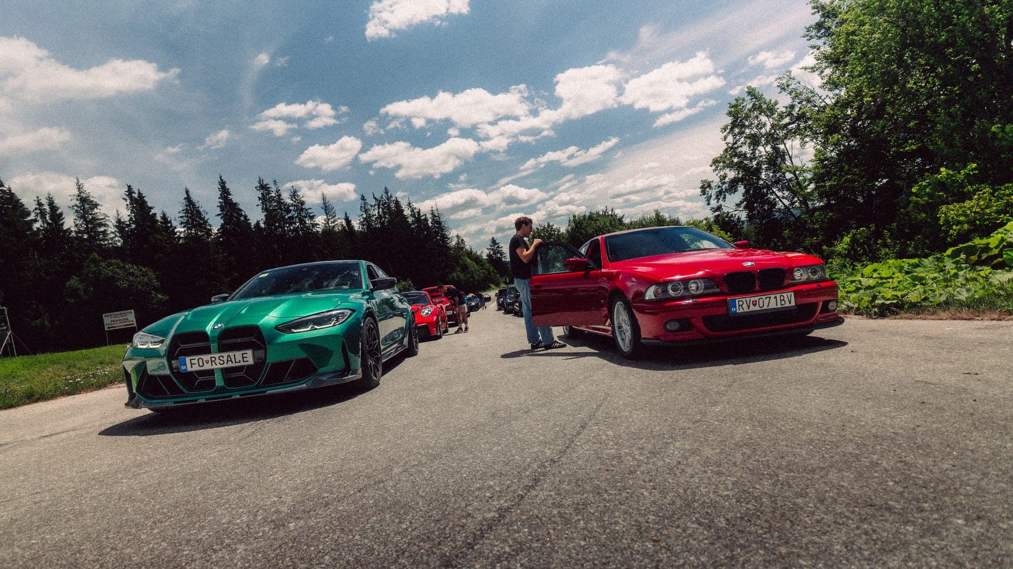 Zelené BMW a červené auto na parkovisku