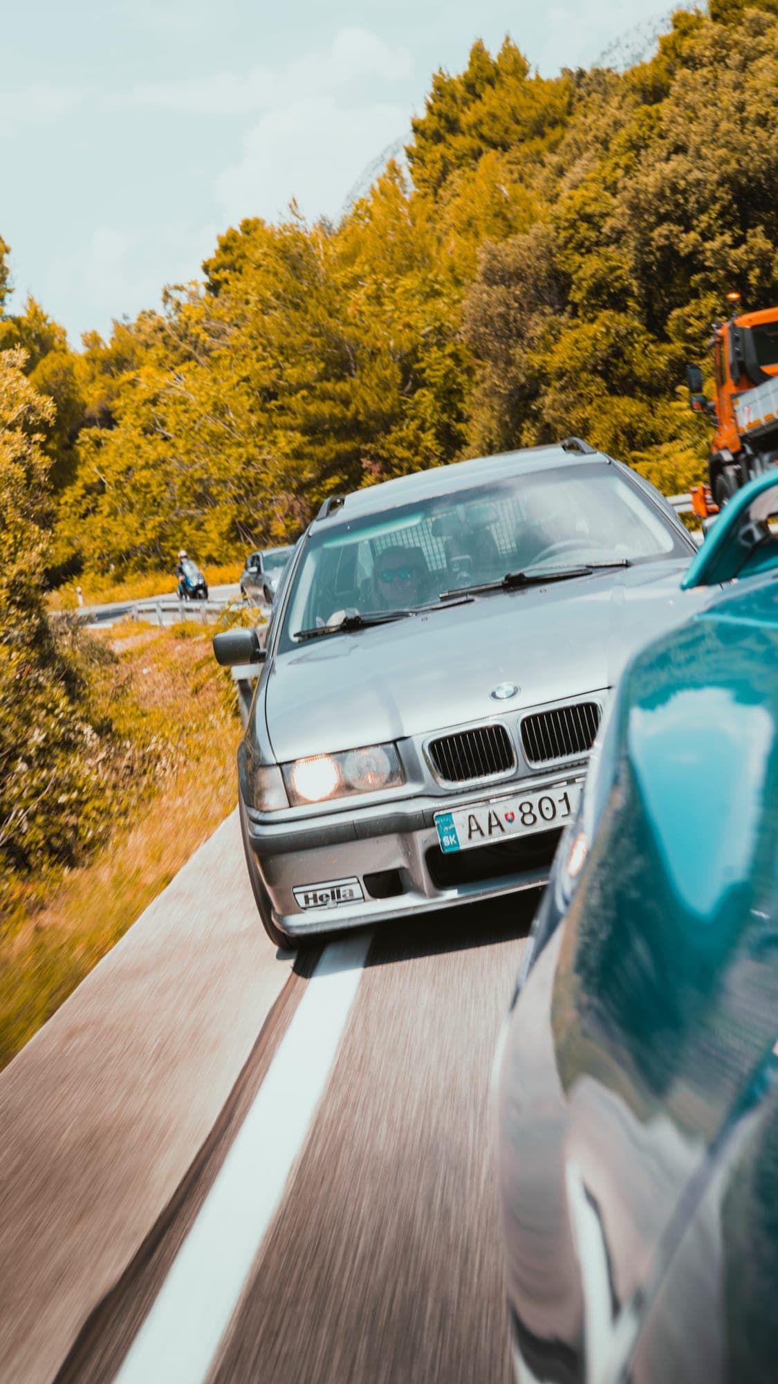 Strieborné BMW na kľukatej ceste, záber z auta vedľa
