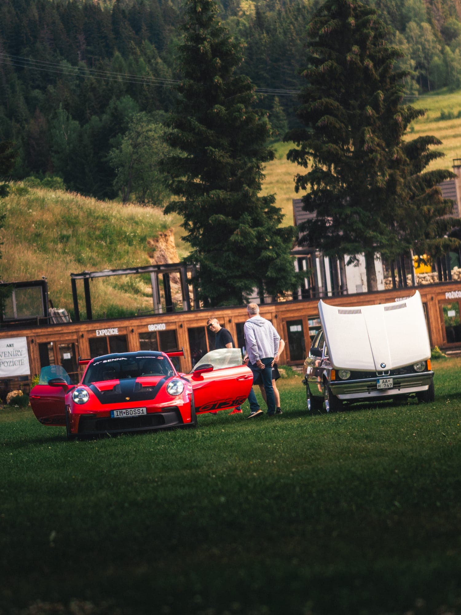 Červené Porsche na lúke pod smrekmi
