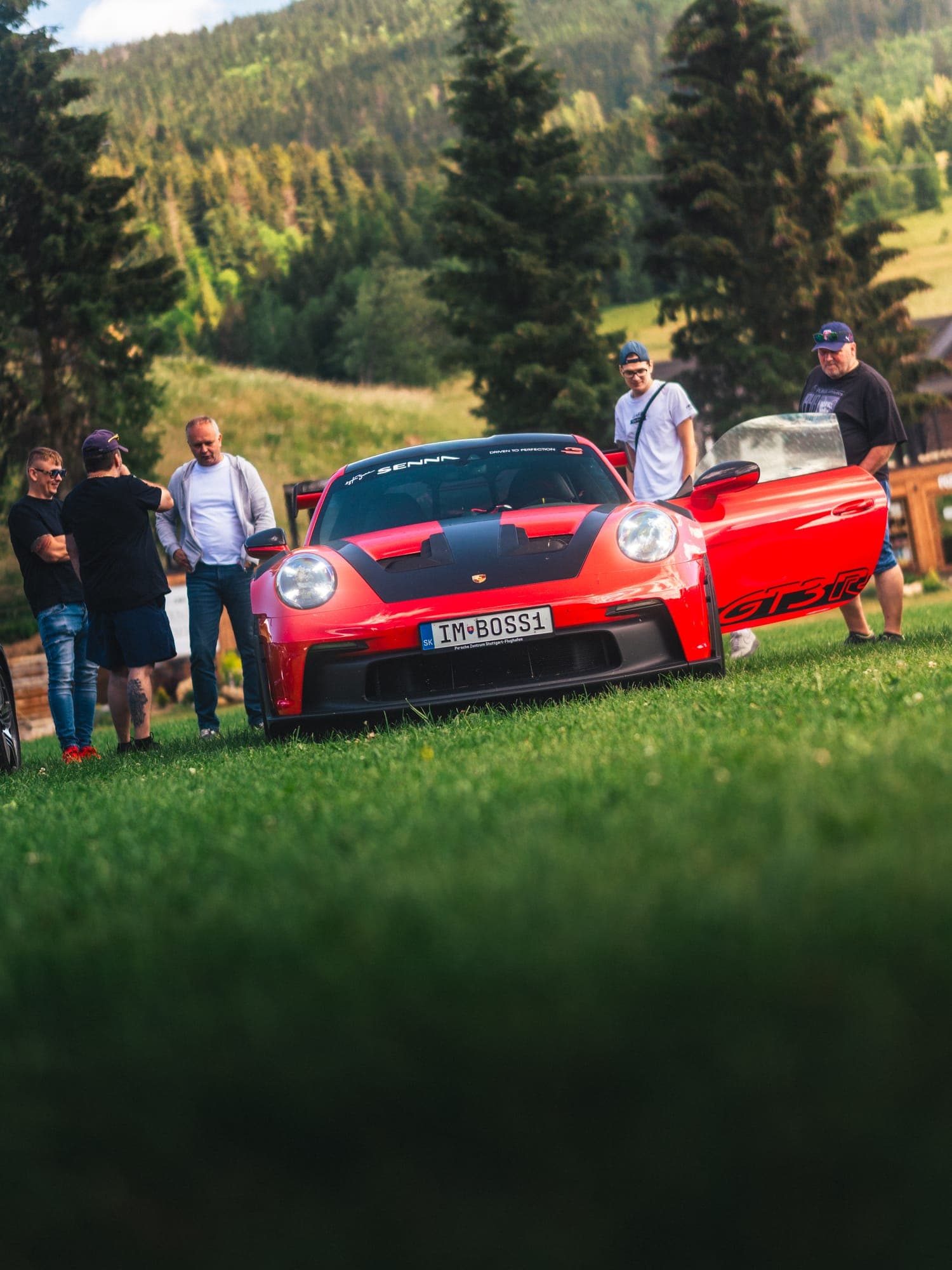 Účastníci zrazu okolo červeného Porsche