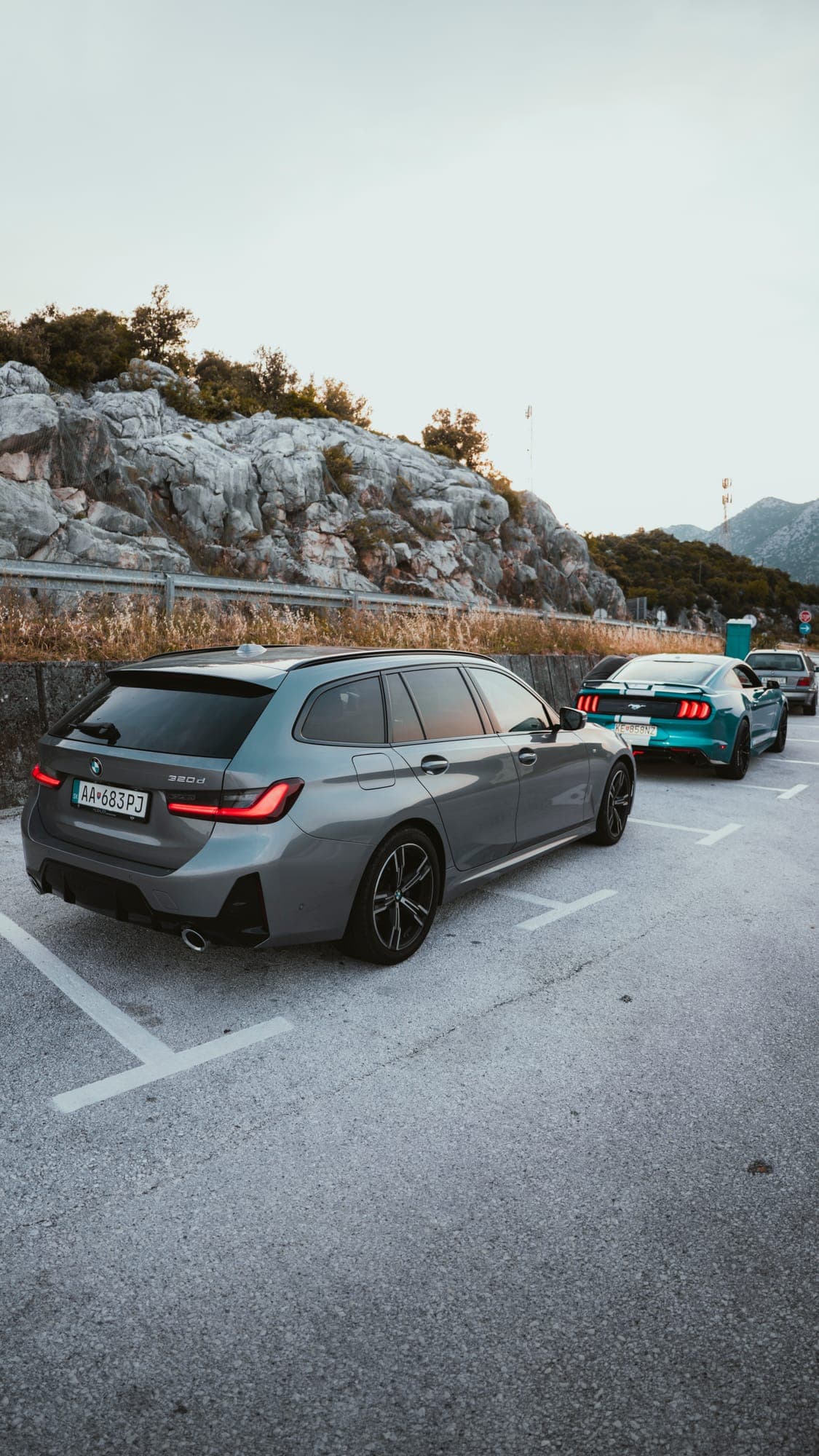 Sivé BMW kombi na parkovisku pod skalami